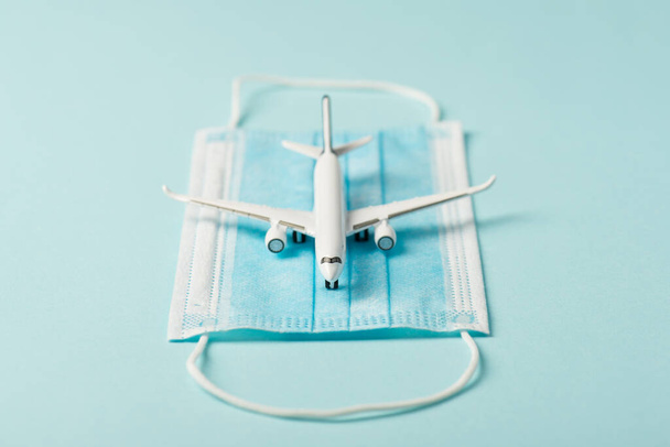 Nahaufnahme Foto des Flugzeugmodells auf medizinischer Maske isoliert blauen Hintergrund mit Kopierraum - Foto, Bild