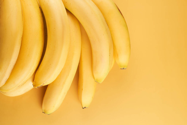 Bunch of whole bananas isolated on yellow background with copy space - Foto, afbeelding