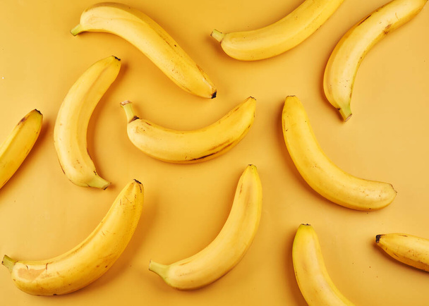 Whole bananas with peel pattern on yellow background, fruits wallpaper - Photo, image