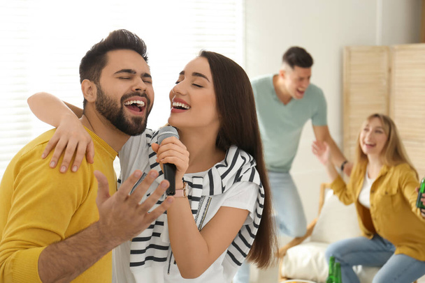 Happy couple singing karaoke with friends at home - Foto, imagen