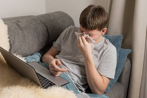 Teenager tries to study online and sneezes into paper towel. Self isolation. Quarantine. Distance elearning. - Foto, Imagem