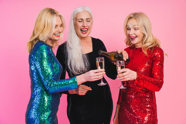 Beautiful senior women with festive elgant dress having fun at a party - Group of sexy mature ladies with eccentric fashionable look poising on clored backgrounds - Concepts about elderly lifestyle - 写真・画像