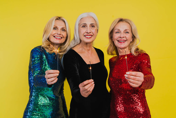 Beautiful senior women with festive elgant dress having fun at a party - Group of sexy mature ladies with eccentric fashionable look poising on clored backgrounds - Concepts about elderly lifestyle - Foto, Imagem