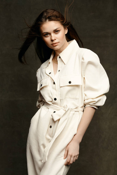 модна жінка модель в білому комбінезоні на темному тлі обрізаний вид впевнений погляд
 - Фото, зображення