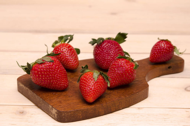 bessen aardbeien op een houten plank close-up op een lichte ondergrond - Foto, afbeelding