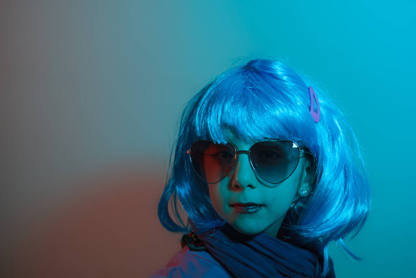 Портрет гламурной маленькой девочки в ярком парике на голубом фоне - Фото, изображение