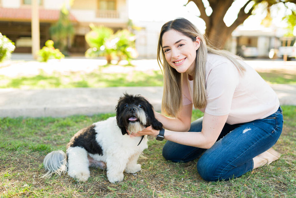 Ritratto di una splendida giovane donna che si gode una giornata di svago al parco con il suo simpatico cane shih tzu. Buon cucciolo seduto all'aperto con il suo proprietario - Foto, immagini
