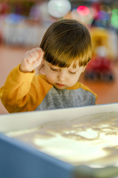 Sviluppo creativo del bambino. Bambino disegna sabbia su vetro. Sviluppo precoce dei bambini. Sviluppo di motilità superficiale e sensazioni tattili. - Foto, immagini
