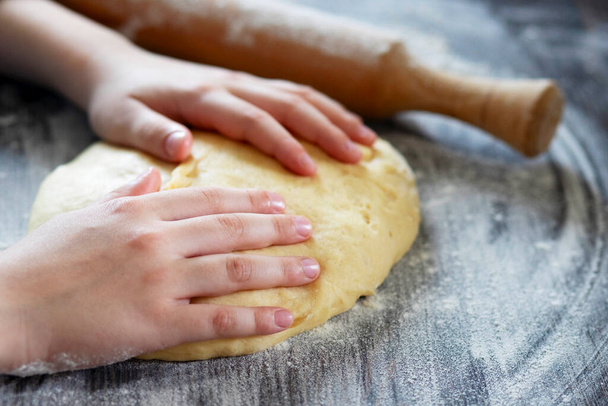 Hands, rolling-pin and dough for bread, pasta or pizza on wooden table. - Photo, Image