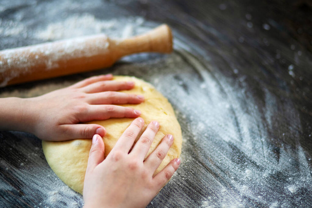 Hands, rolling-pin and dough for bread, pasta or pizza on wooden table. - Foto, Imagen