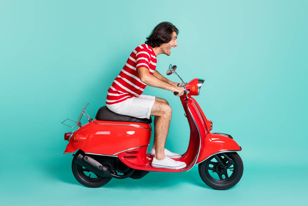 Profile side view of handsome cheerful guy driving moped having fun hurry rush isolated over bright green turquoise color background - Фото, изображение