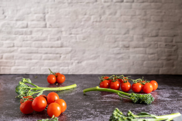 Food photography of fresh cherry tomatoes and bimi on a stone table with brick wall. Still life image with a copy space. - Фото, зображення