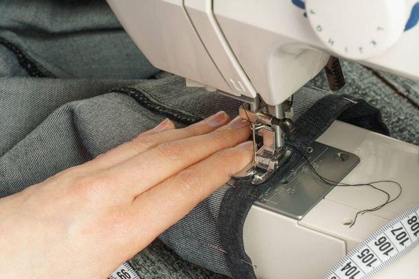 proces zkrácení džínových kalhot na šicím stroji - Fotografie, Obrázek