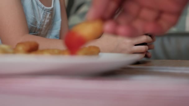 Lähikuva VDO näyttää Lapsen käsi pakottaa Joystick pelata videopelejä ja syö pikaruokaa, Valkoinen ruokalaji ranskalaisia perunoita, kimpaleita, ja ketsuppia. Online viihde teknologia tekee lapset riippuvaisiksi. - Materiaali, video