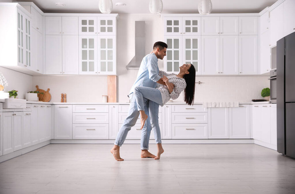 Happy couple dancing barefoot in kitchen. Floor heating system - Photo, image