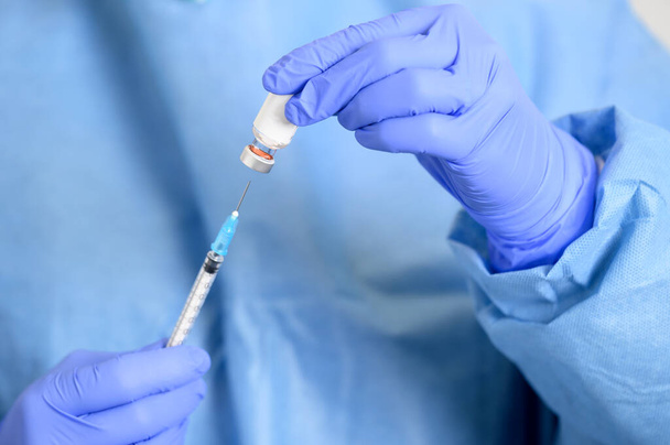 Doktor elinde bir şişe Covid-19 aşısı olan bir şırınga tutuyor. Virüse karşı kavramsal mücadele. Ayrıntıları kapat. Tıbbi konsept aşı derialtı enjeksiyon tedavisi. - Fotoğraf, Görsel