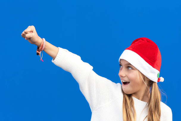 Joven alegre en Santa sombrero gesto sobre fondo azul. - Foto, imagen