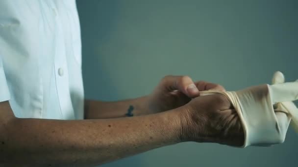 Vrouwelijke dokter doet Rubber Handschoenen aan tijdens de Coronavirus Pandemie. Close-Up.   - Video