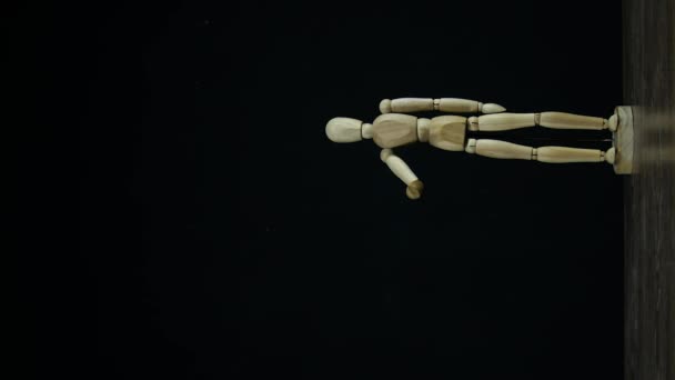 Verticale video Stopbeweging houten figuur dummy zwaaiende arm in studio op zwarte achtergrond, afscheid nemen - Video