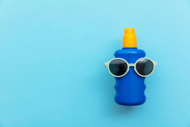 Summer holiday vacation background. Bottle of sun cream with sunglasses - Fotó, kép