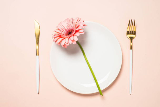 Asztalbeállítás fehér tányérral, evőeszközökkel és virágokkal. - Fotó, kép