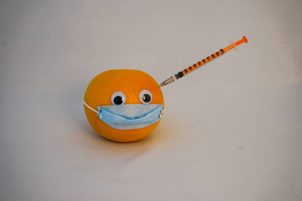 pomelo naranja con máscara quirúrgica durante la epidemia de covidio - Foto, Imagen