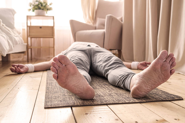 Blanke man mediteren op een houten vloer en liggen in Shavasana pose - Foto, afbeelding