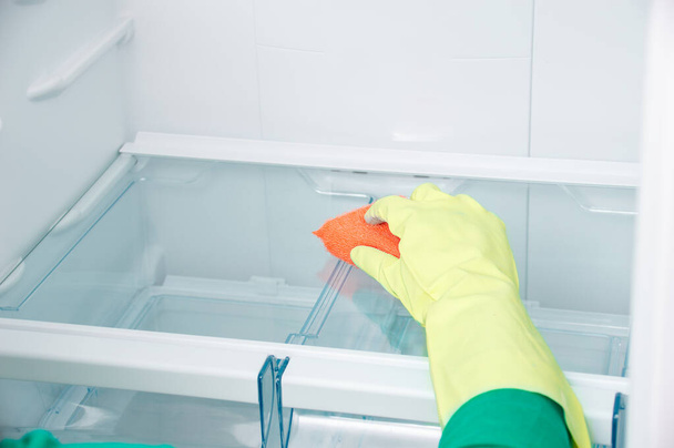 Evde kırbaçlı kadın el temizleme buzdolabı var. - Fotoğraf, Görsel