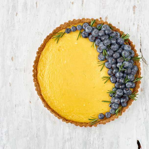 Tart with lemon curd and fresh blueberry on a light wooden background. Copy space, selective focus, top view - Foto, Bild