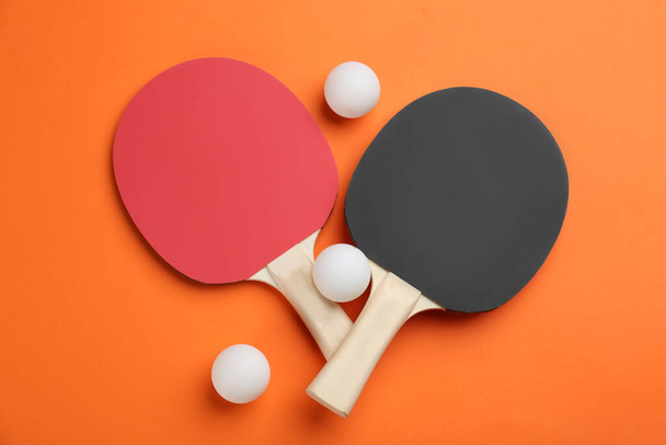 Ping pong rackets and balls on orange background, flat lay - 写真・画像