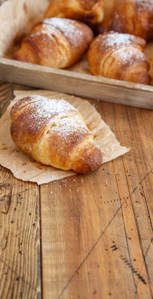 French fresh crusty croissants on a wooden table close up - Photo, Image