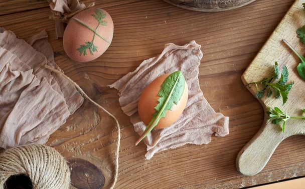 Příprava velikonočních vajec k uhynutí s cibulovými slupkami se vzorkem čerstvých bylin - Fotografie, Obrázek