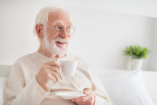 Photo of aged man happy positive smile enjoy morning cup of hot tea dream dreamy look empty space home - Фото, изображение