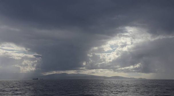 Tengeri, sok árnyalatú szürke: a víz felszínén, egy csík part és vastag felhők az égen. - Fotó, kép