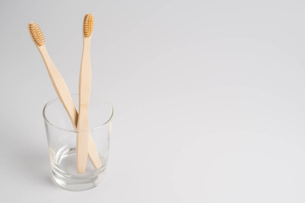 Bambu diş fırçası beyaz arka planda izole edilmiş camda. Sıfır atık, biyolojik olarak ayrıştırılabilir bambu diş fırçası. - Fotoğraf, Görsel