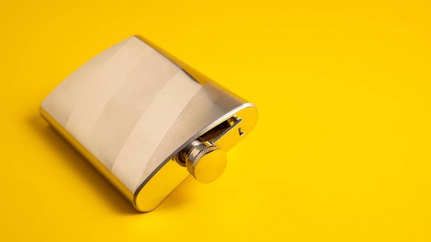 Metal pocket bottle. Stainless hip flask isolated on a yellow background. Steel flask. Steel bootle. Aluminum hip flask - Fotografie, Obrázek