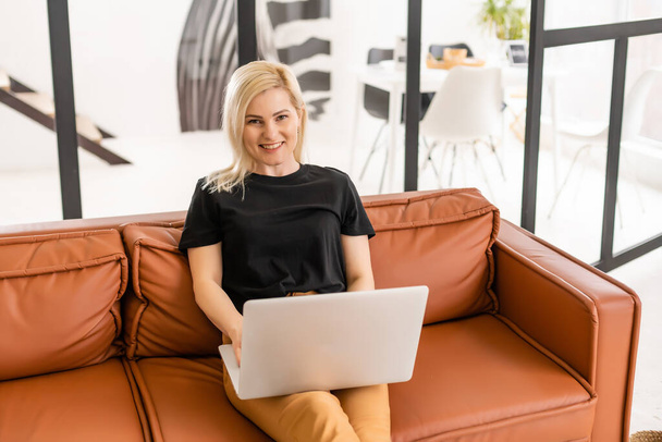 Happy casual piękna kobieta pracuje na laptopie siedzi w domu. - Zdjęcie, obraz