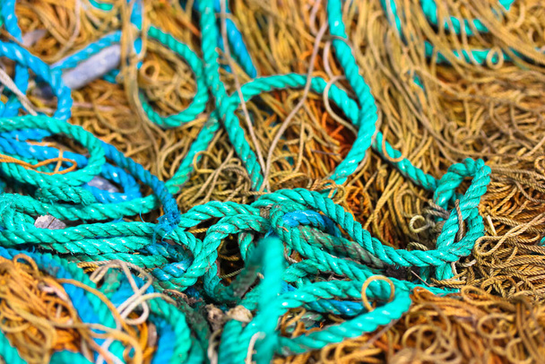 Verschillende ruwe touwen verspreid in een chaotische volgorde, bekijken van bovenaf. Bruine en blauwe touwen van boven. Marinestructuur. Maritieme touwen textuur close-up. Veiligheidstouw textuur.  - Foto, afbeelding