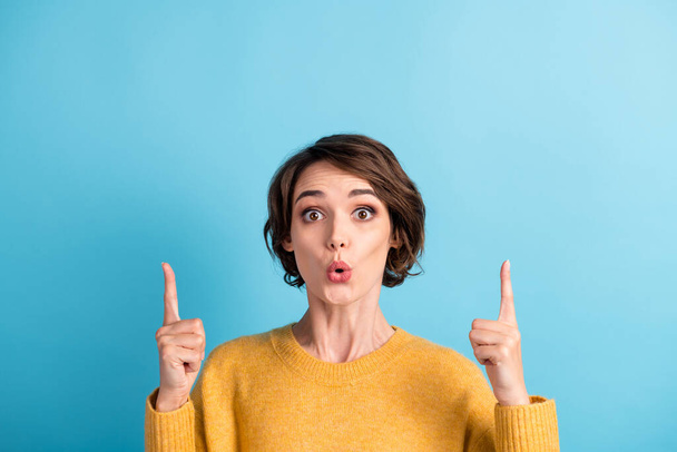 Photo portrait of surprised girl with bob hairstyle pointing up at copyspace with fingers staring isolated on vivid blue color background - Foto, imagen