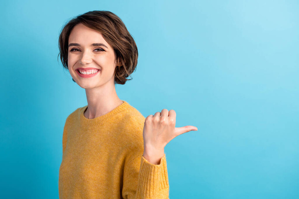 Portrait photo d'une fille joyeuse portant un pull pointant vers un espace vide avec le doigt riant isolé sur fond de couleur bleu vif - Photo, image