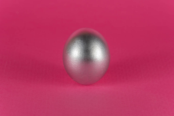Uovo d'argento su sfondo rosa scuro. Sfondo astratto Pasqua - Foto, immagini