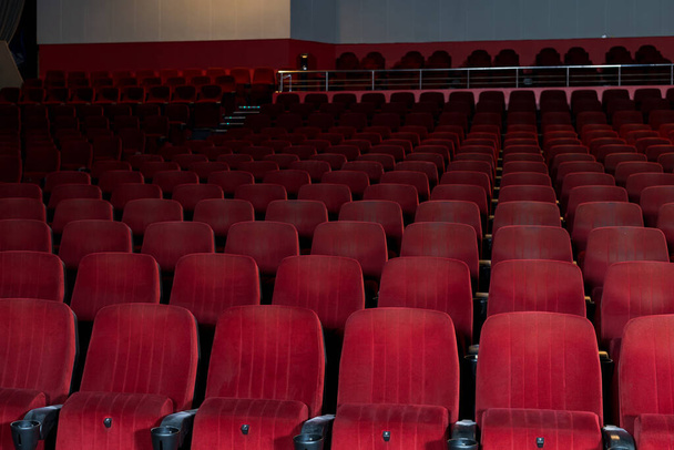Lege rijen stoelen in een bioscoop of concertzaal. Stoelen zonder toeschouwers. Afsluiting en beperkingen tijdens de COVID-19 pandemie - Foto, afbeelding