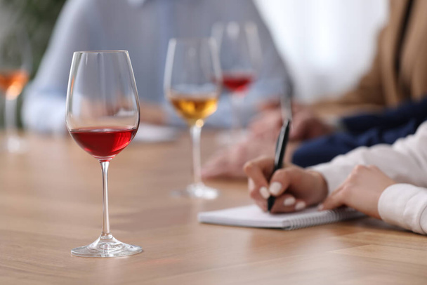 Sommeliers making notes during wine tasting at table indoors, closeup - Фото, изображение