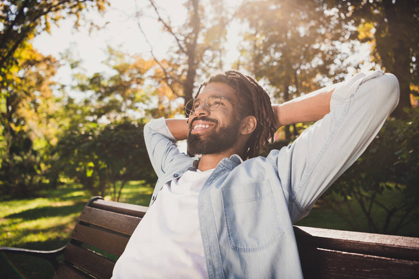 Photo portrait of man in glasses smiling relaxing on bench wearing shirt in sunny summer day - Photo, Image