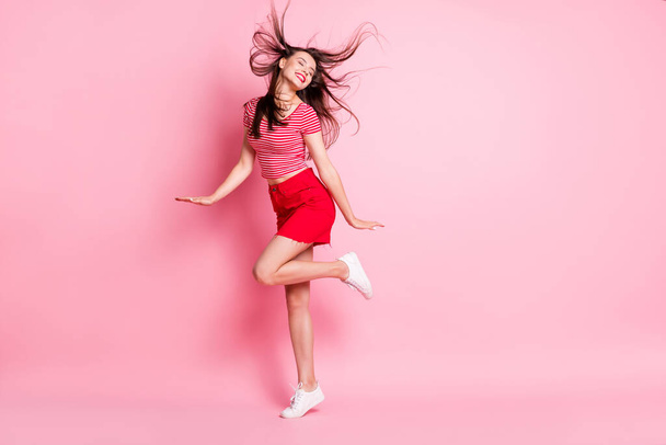 Full size photo of young attractive energetic active smiling cheerful girl with flying hair isolated on pink color background - Foto, immagini