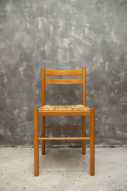 Foto de silla de mimbre en la pared de hormigón gris en el interior, espacio vacío, espacio de copia para el texto. Elemento interior, muebles - Foto, Imagen