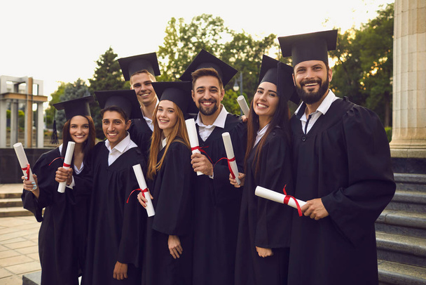 Group of graduate students in graduation gowns near university campus. - Foto, Imagen