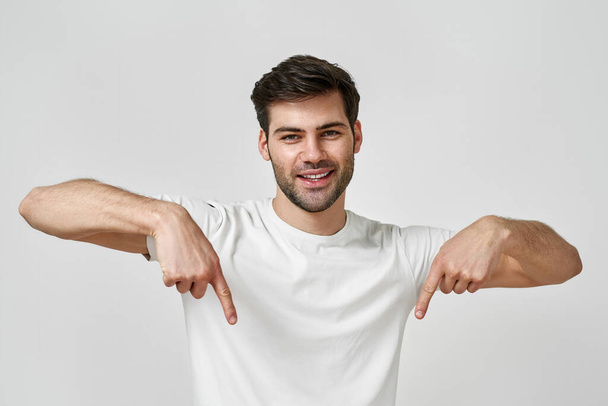 Man in white t-shirt with thumbs down gesture - Fotografie, Obrázek