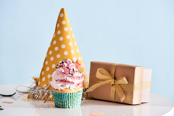 Fond de fête d'anniversaire avec cupcake, chapeau de fête et cadeau - Photo, image