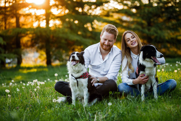Young couple in love walking and enjoy time in park with dogs. Dog people adoption concept - Photo, Image
